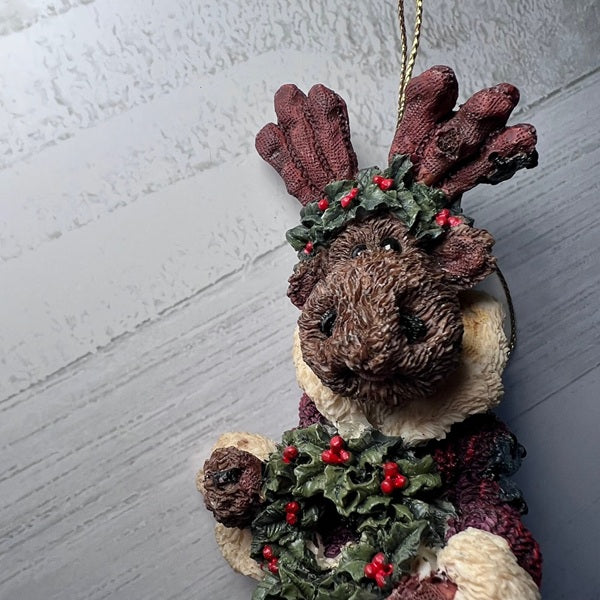 Decorative reindeer ornament with antlers and holly decorations on a plain background