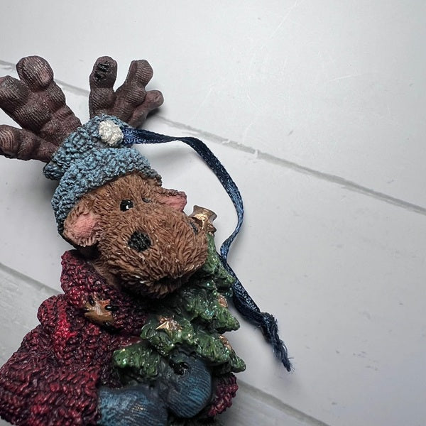 Decorative figurine of a moose with a blue hat and scarf on a white background