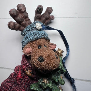 Resin moose ornament with knitted hat and scarf on a white background