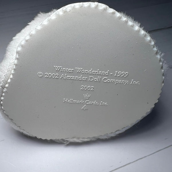 Back of a white ornament with branding text on a gray background