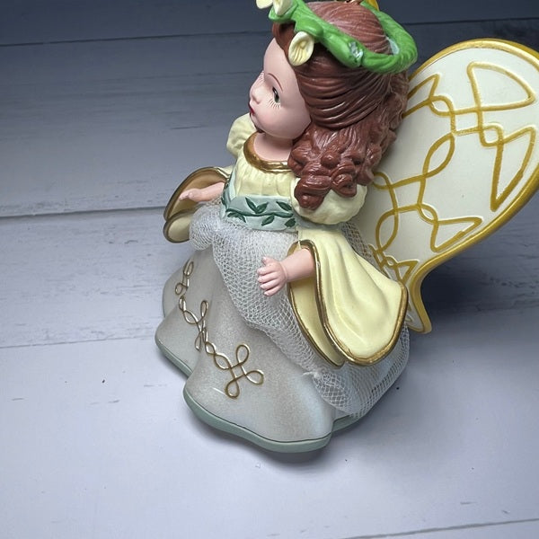 Decorative angel figurine with floral crown on a light wooden background