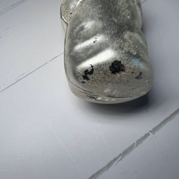 Metallic object with a textured surface on a light gray floor