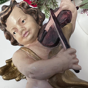 Statue of an angel holding a violin against a white background