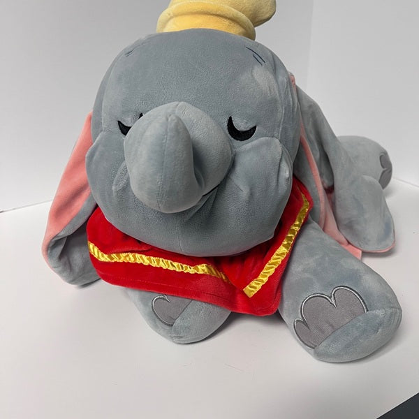 Plush toy of Dumbo the elephant with a red cape on a white background