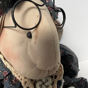 Close-up of a fabric rabbit with glasses and floral headband on a white background