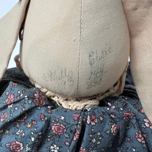 Close-up of a vintage doll with floral dress and embroidered details.
