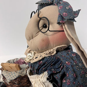 Textile art doll with floral headscarf, glasses, and basket on a white background