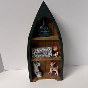 Wooden boat-shaped shelf with decorative items on a white background