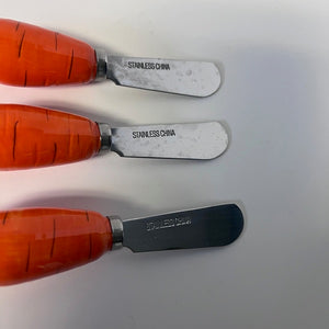 Three spreaders with orange handles and metal blades on a white background