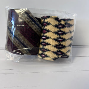 Two patterned ties in a clear plastic bag on a white surface
