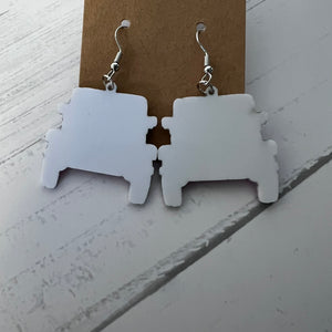 White puzzle piece earrings on a brown card against a white background
