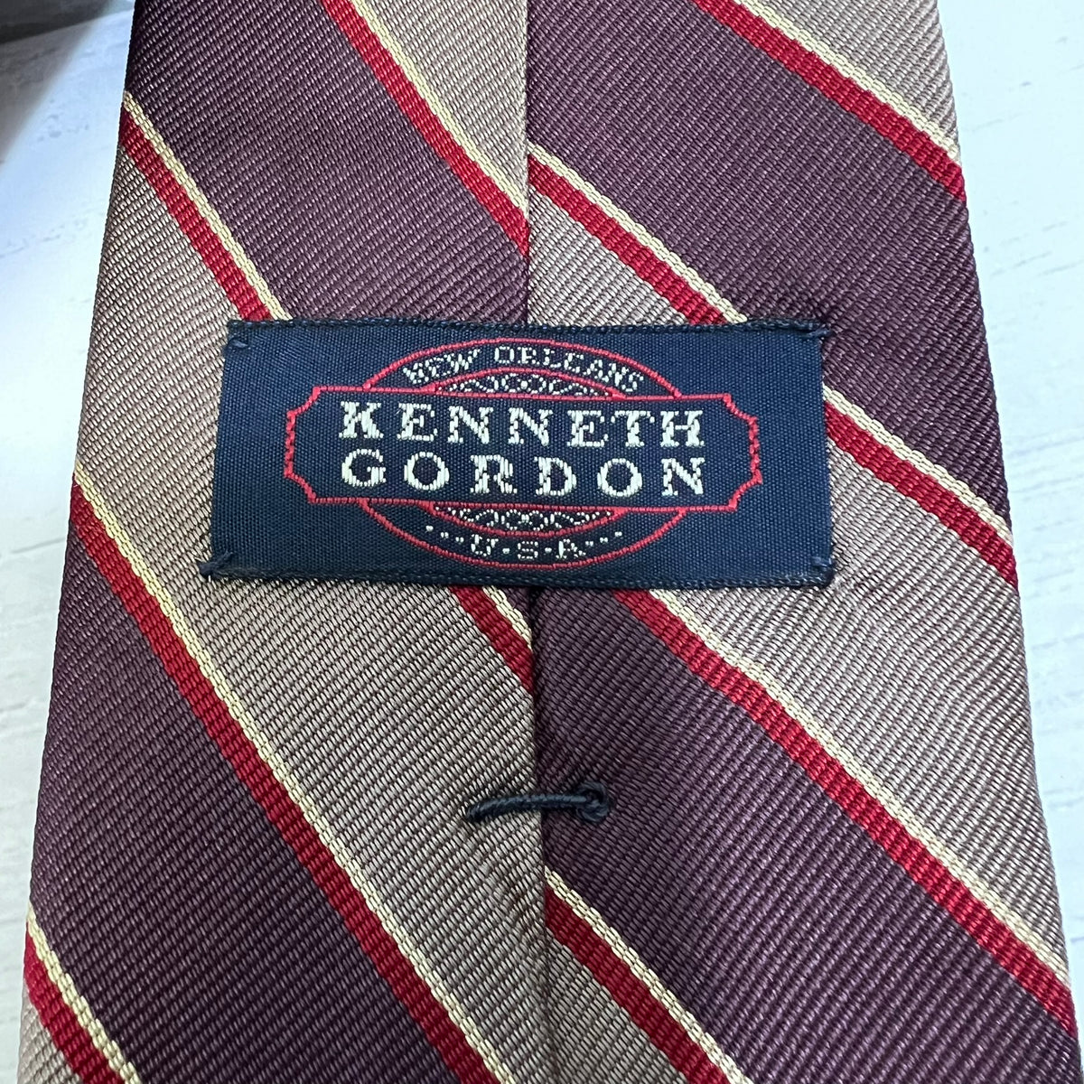 Striped tie with a Kenneth Gordon label on a white background