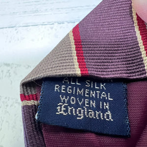 Close-up of a silk regimental tie with a label indicating it is woven in England.