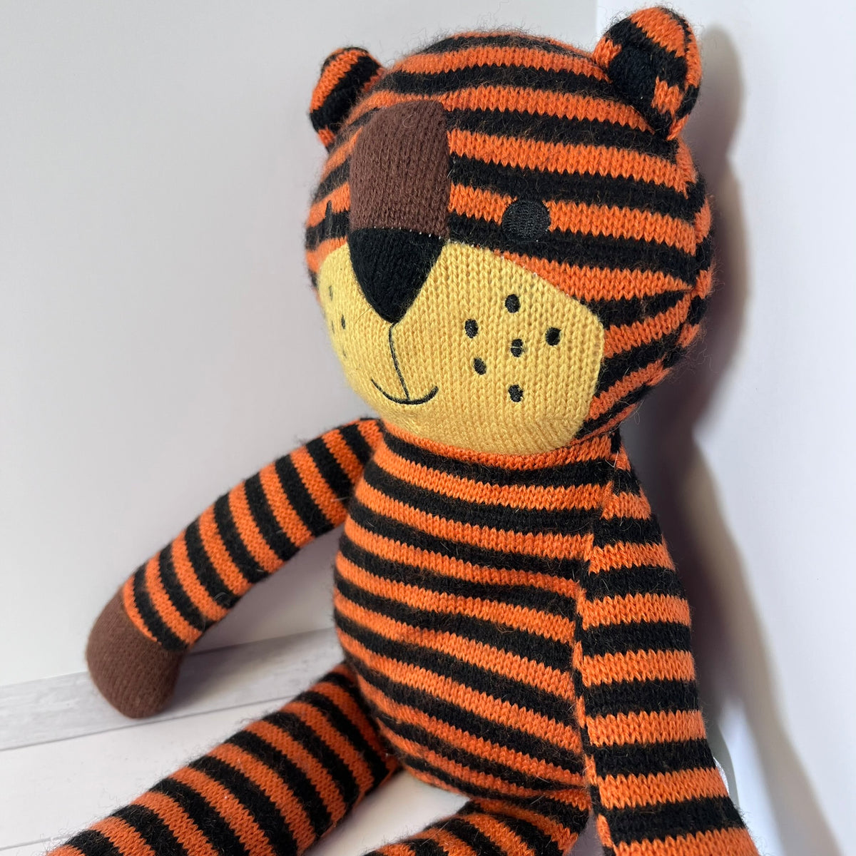 Knitted tiger toy with black and orange stripes on a white background