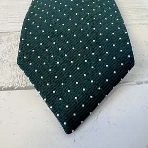 Dark green tie with white polka dots on a light gray surface