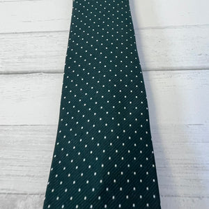 Green tie with white polka dots on a light wooden surface