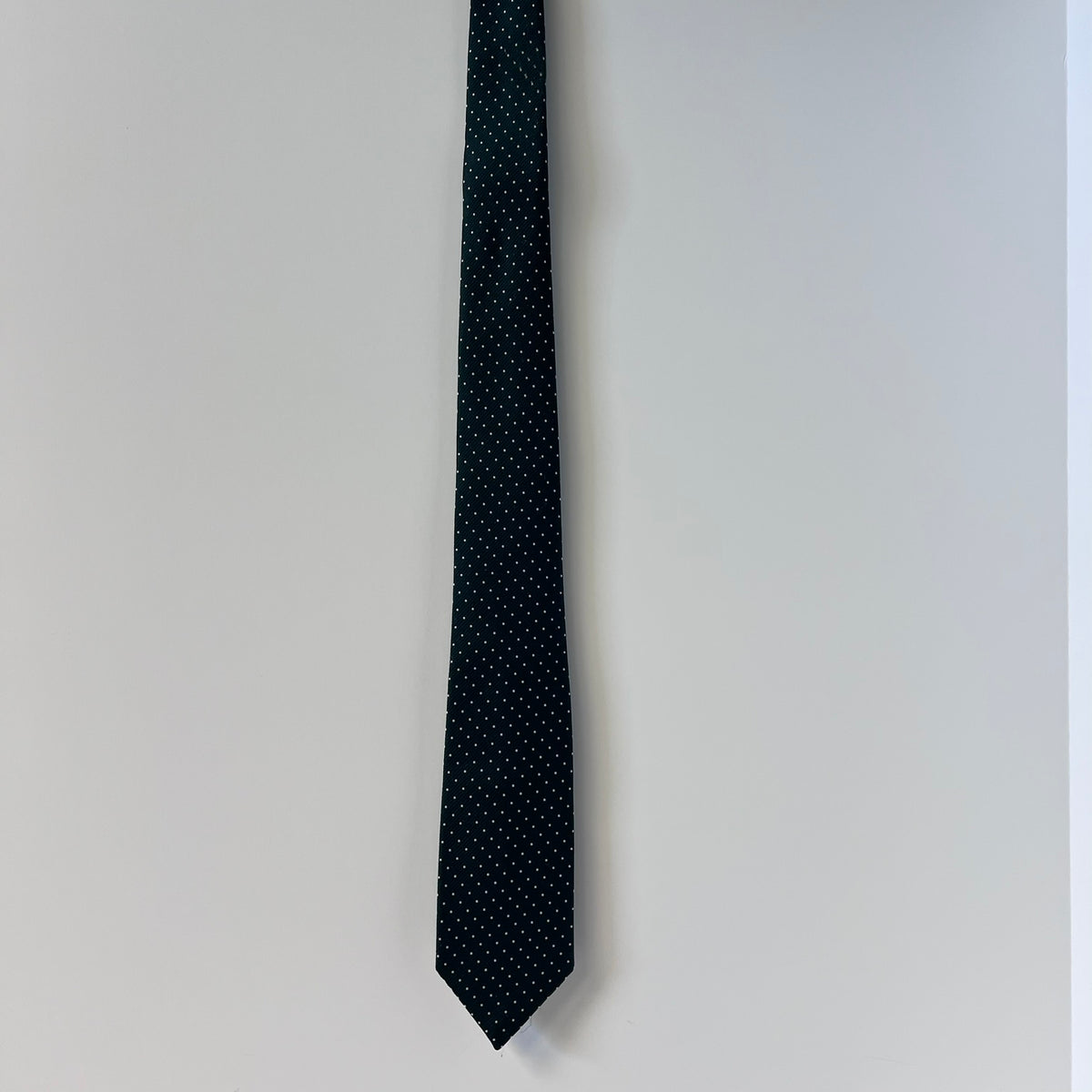 Black tie with white polka dots on a light gray background