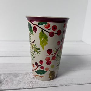 Decorative ceramic cup with holly design on a white surface