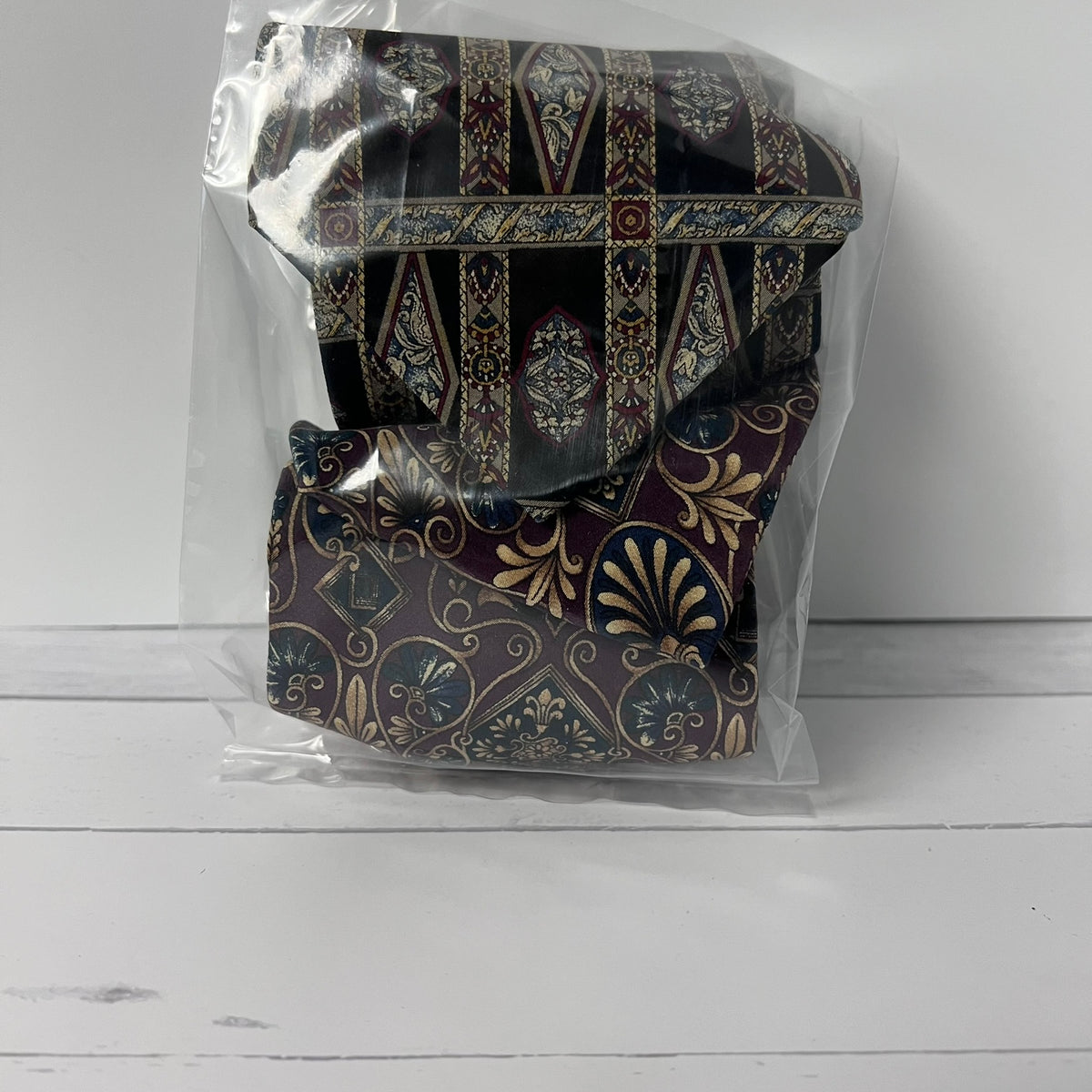 Patterned tie in a clear plastic bag on a white surface