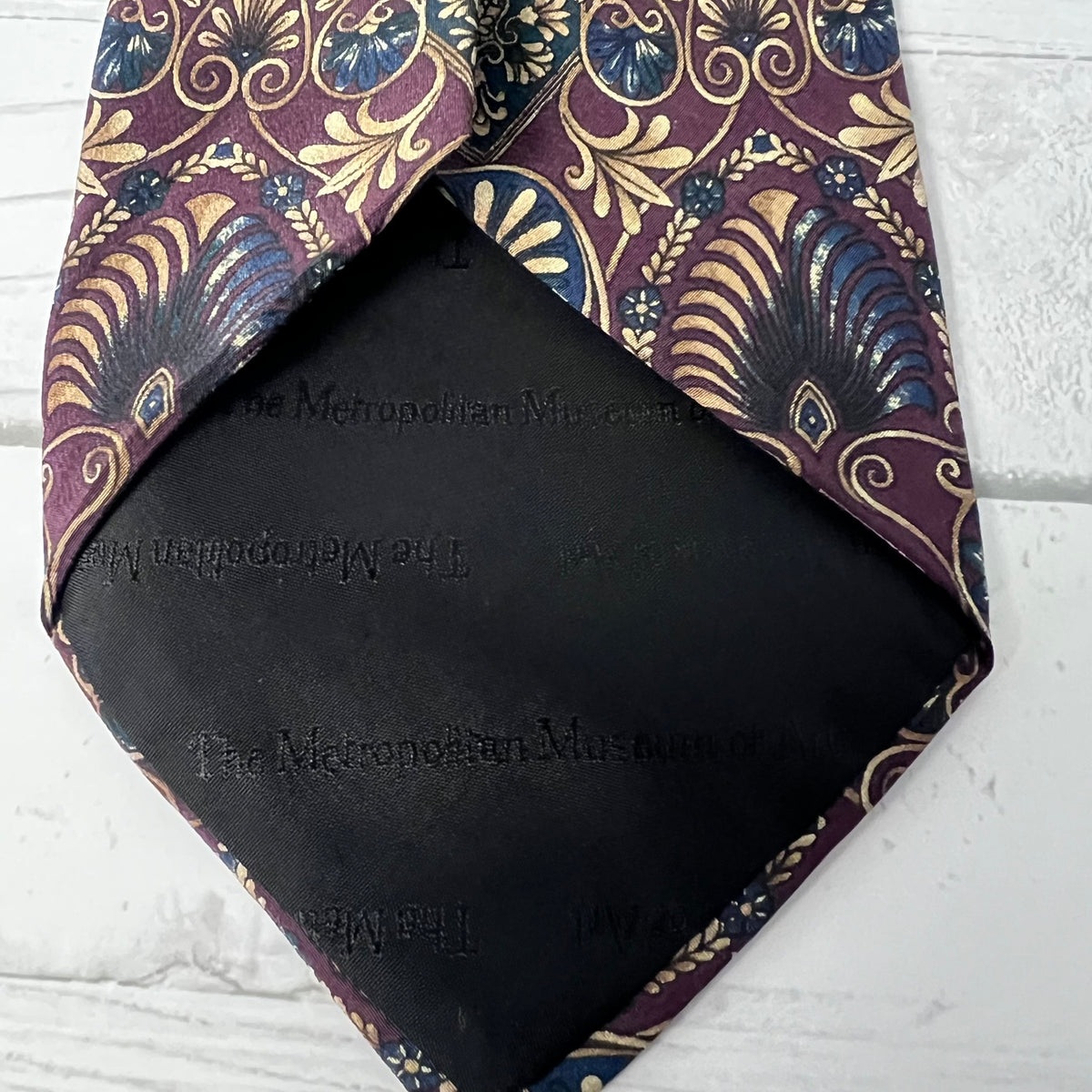 Black fabric with 'The Metropolitan Museum of Art' branding and a patterned purple tie on a white background