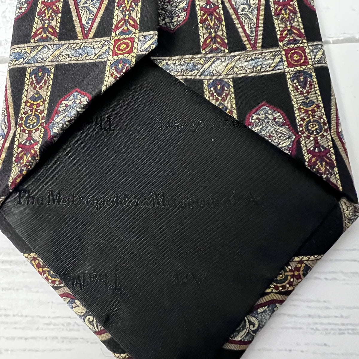 Black pocket square with patterned tie on a white background