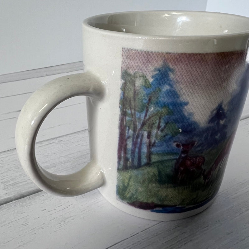 Mug with a scenic design of trees and a deer on a white surface