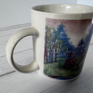 Mug with a scenic design of trees and a deer on a white surface