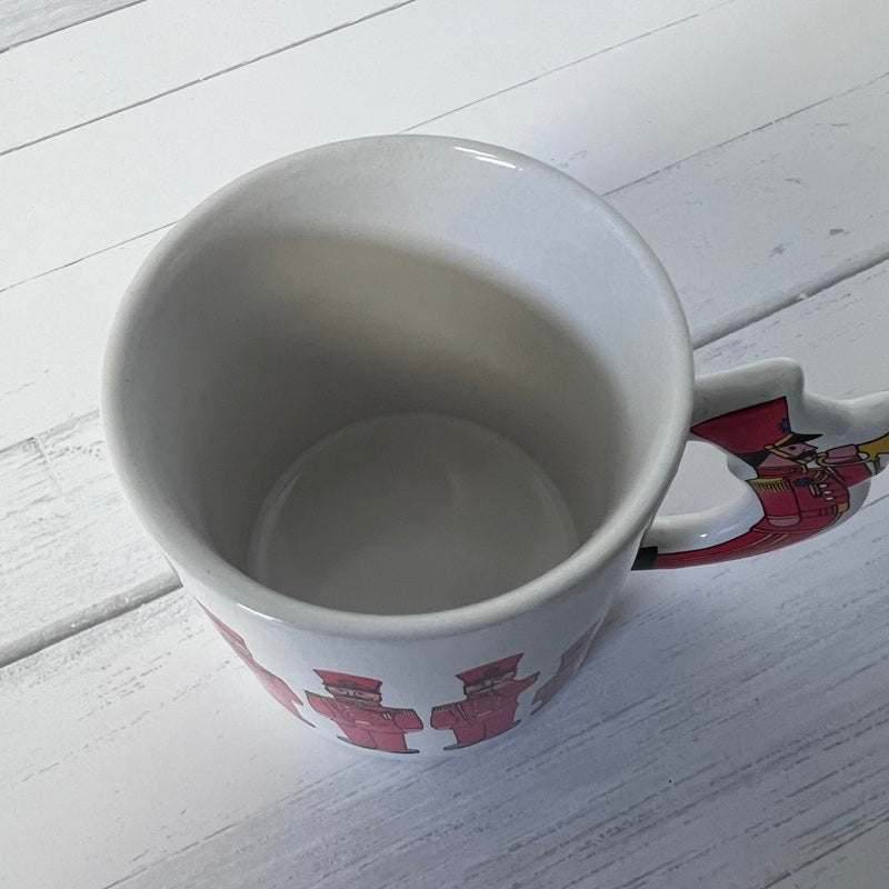 White mug with red and yellow design on a white wooden surface