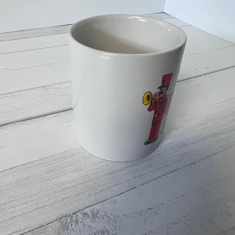 White mug with a colorful illustration of a character on a white wooden surface