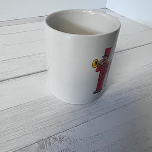 White mug with a colorful illustration of a character on a white wooden surface
