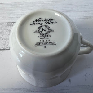 White ceramic cup with 'Noritake Ivory China' branding on a light wooden surface