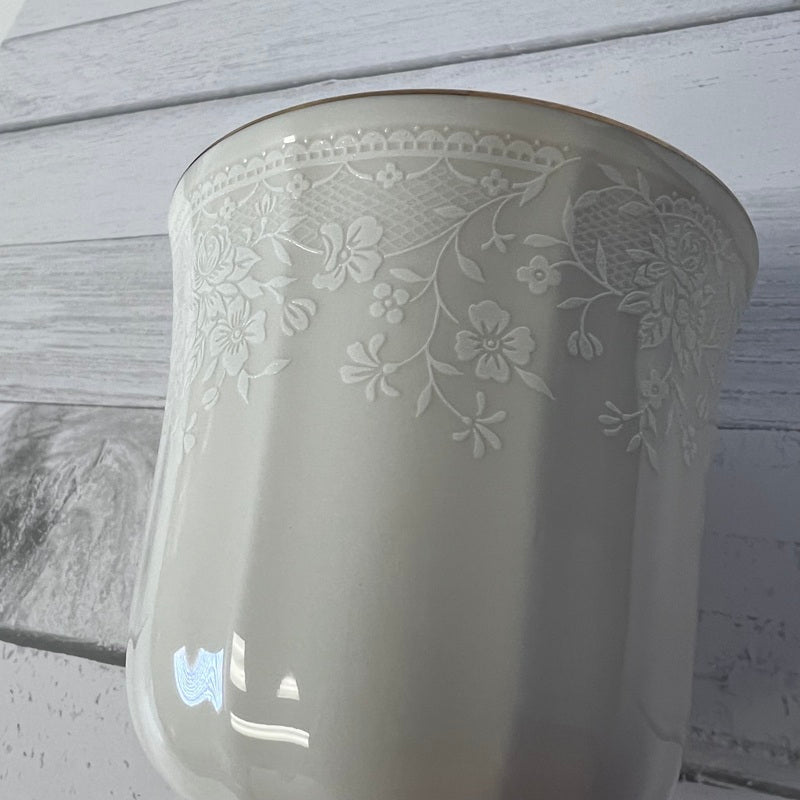White ceramic vase with floral patterns on a wooden surface