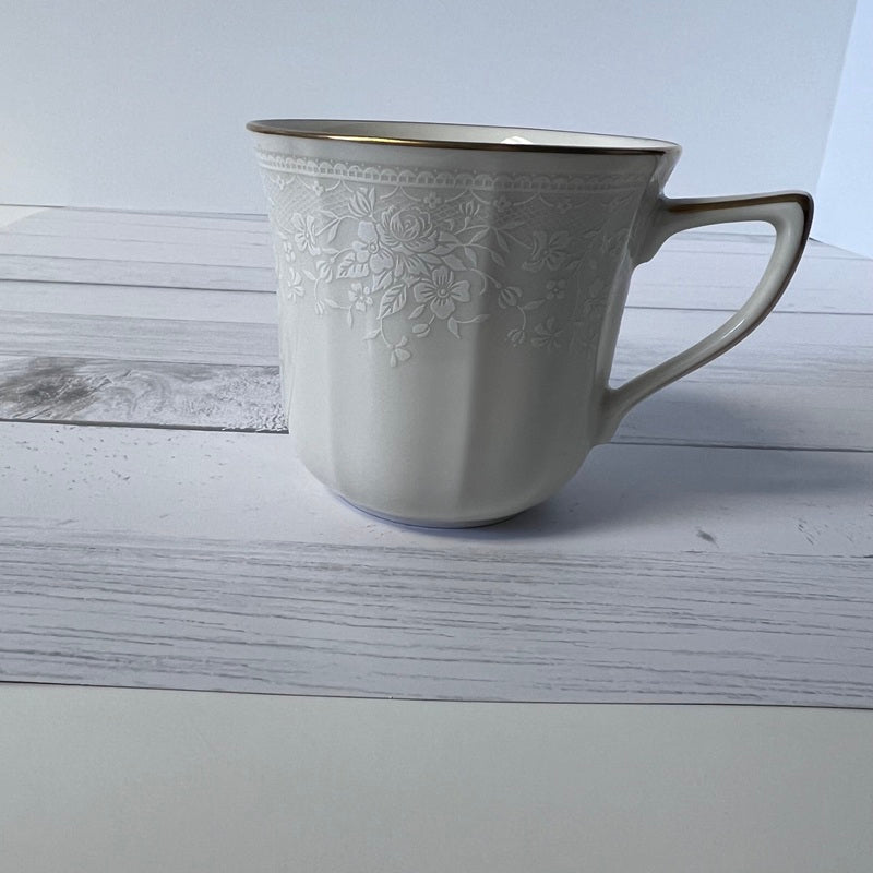 White ceramic mug with floral patterns on a wooden surface