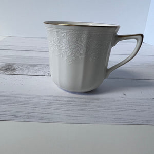 White ceramic mug with floral patterns on a wooden surface