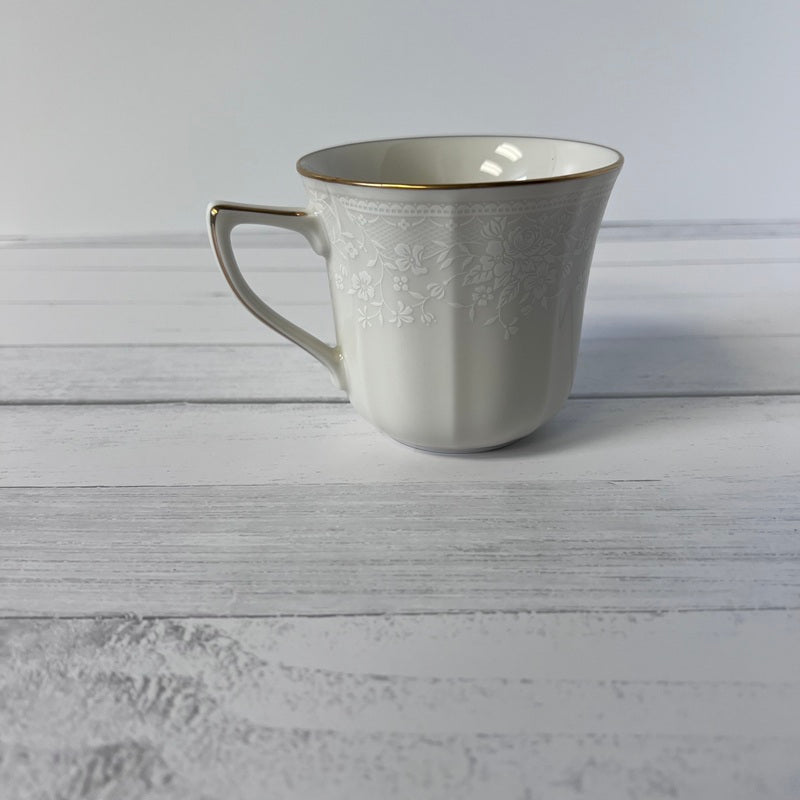 White ceramic mug with gold interior on a light wooden surface