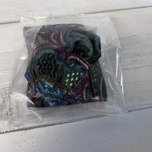 Colorful patterned fabric item in clear packaging on a white wooden surface