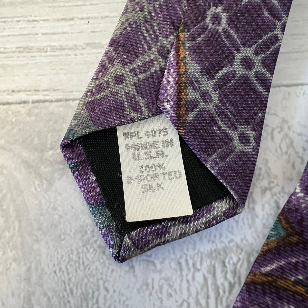 Close-up of a patterned tie with a label on a textured surface