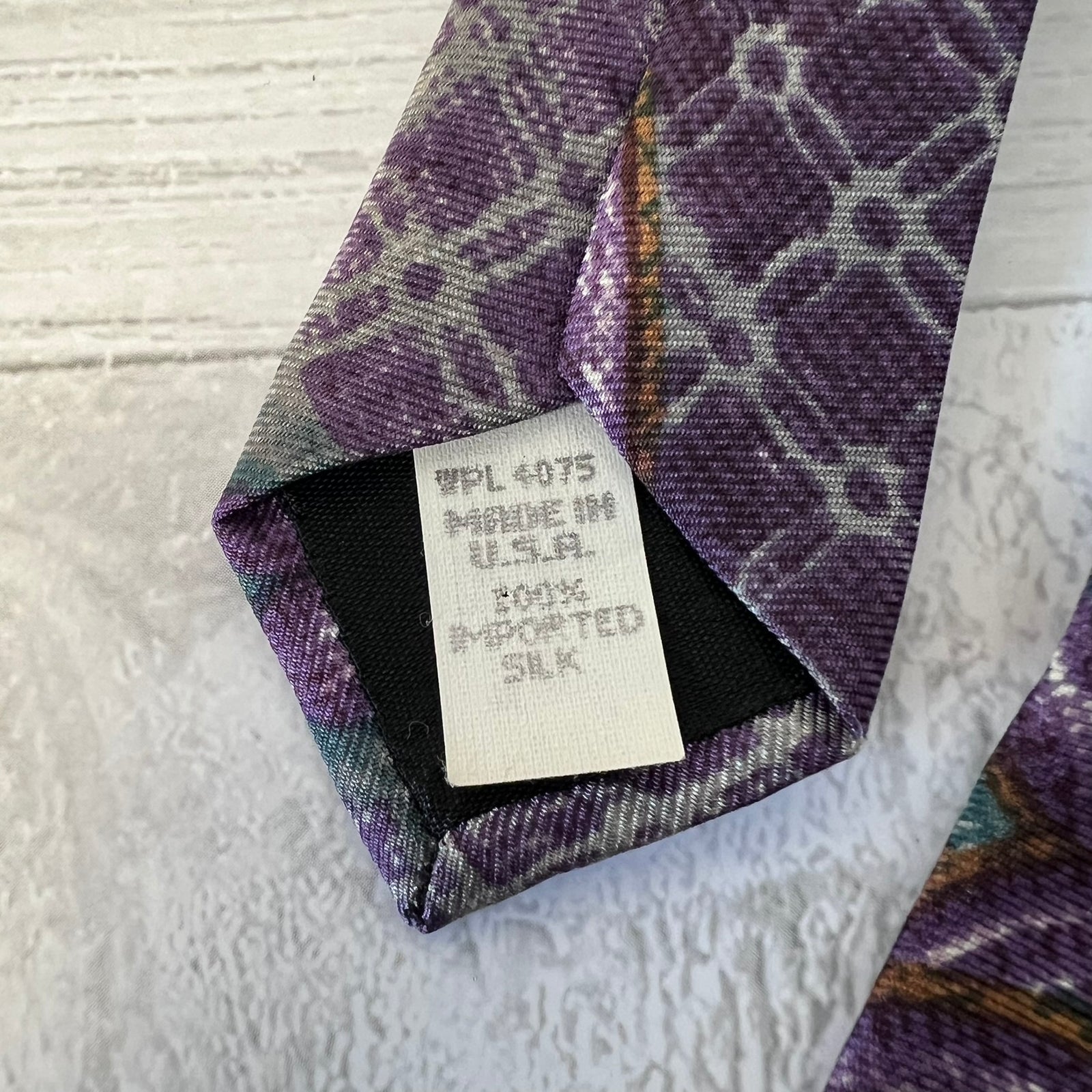Close-up of a patterned tie with a label on a textured surface
