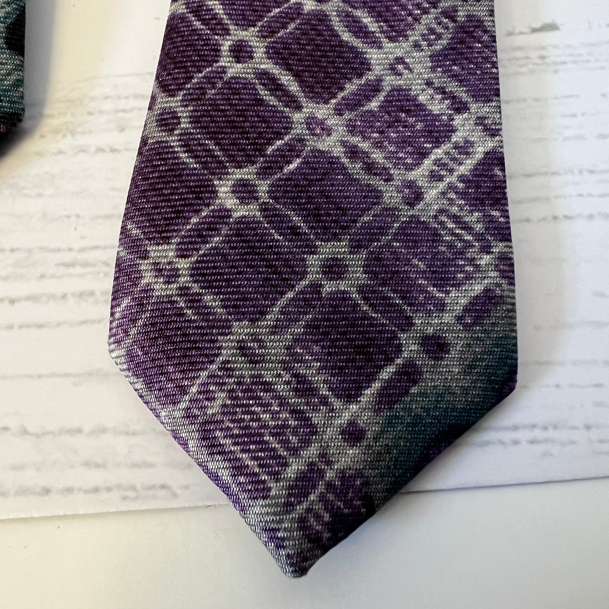 Purple and gray plaid tie on a white surface