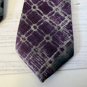 Purple and gray plaid tie on a white surface