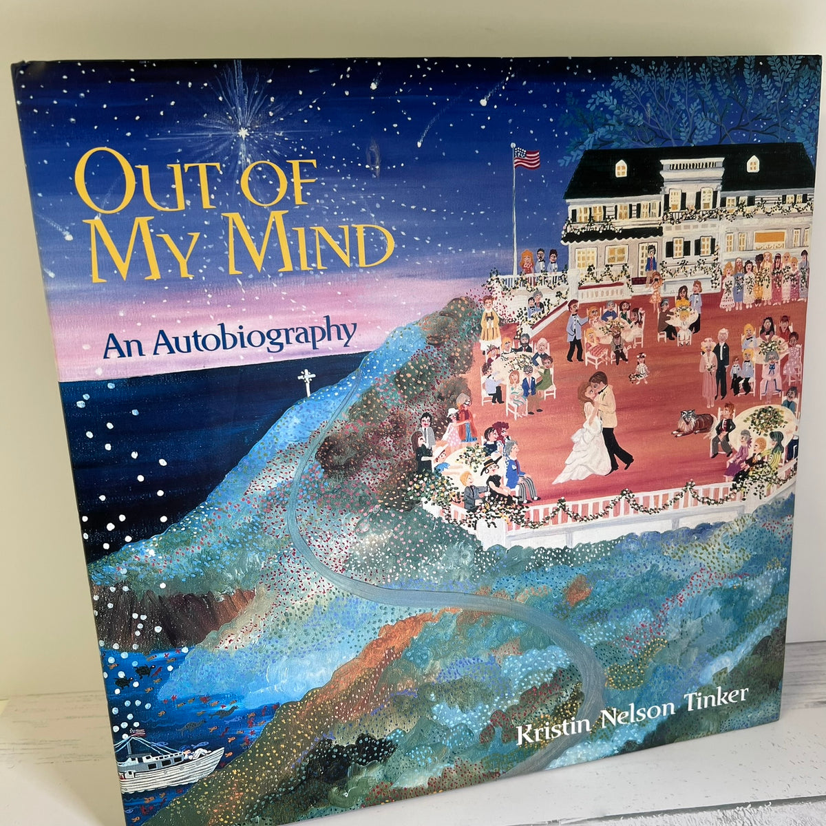 The front cover of the book 'Out of My Mind: An Autobiography' by Kristin Nelson Tinker, featuring a colorful, textured illustration of a wedding scene on a hillside under a starry night sky.