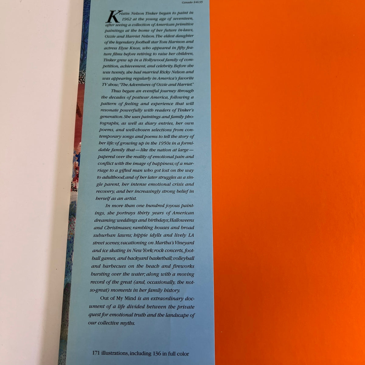 A printed book or booklet page with a large black text column on a white background, photographed against a blue-and-white striped surface with a warm orange glow on the right side.