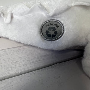 White plush toy with a recycling symbol label on a wooden surface