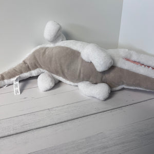 Plush toy shark on a light wooden floor with a white wall background
