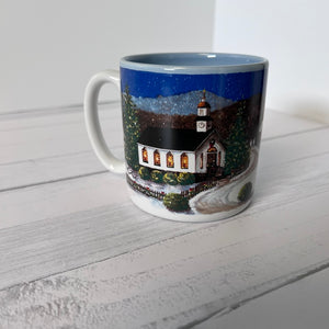 Mug with a winter scene of a church on a white wooden surface