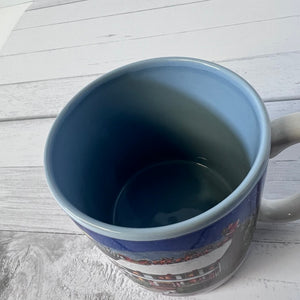 Blue mug with a scenic design on a wooden surface