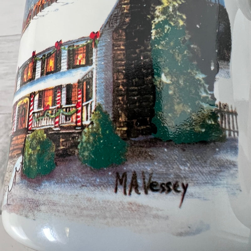 Mug with a winter scene of a house and trees, signed 'MA Vessey'.