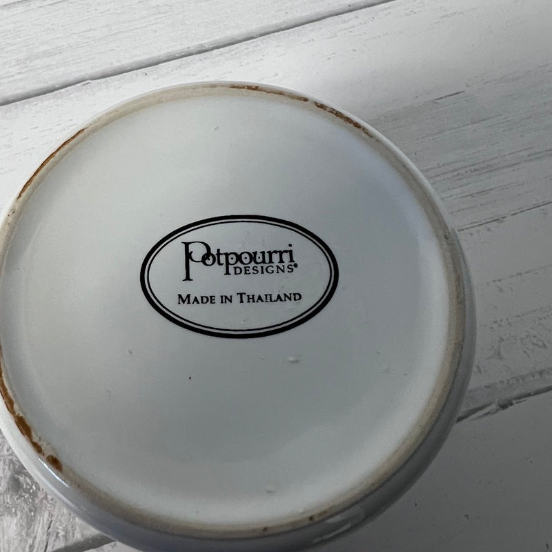 White ceramic dish with 'Polpourri Designs' logo on a light wooden surface