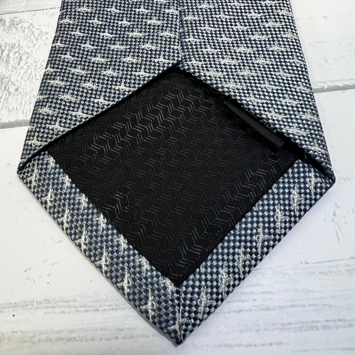 Black textured square on a gray and white patterned fabric background