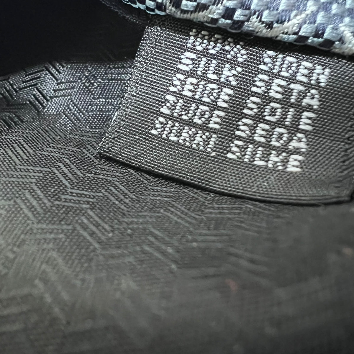Close-up of a textured black cap with brand name on a dark background